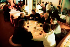 Six men enjoy drinks and conversation at a cozy Barcelona restaurant ideal for MIT Creators corporate events in 2025.