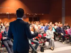 Business professional presenting at a corporate event in Barcelona, organized by MIT Creators DMC. Engaged audience at Spain roadshow.